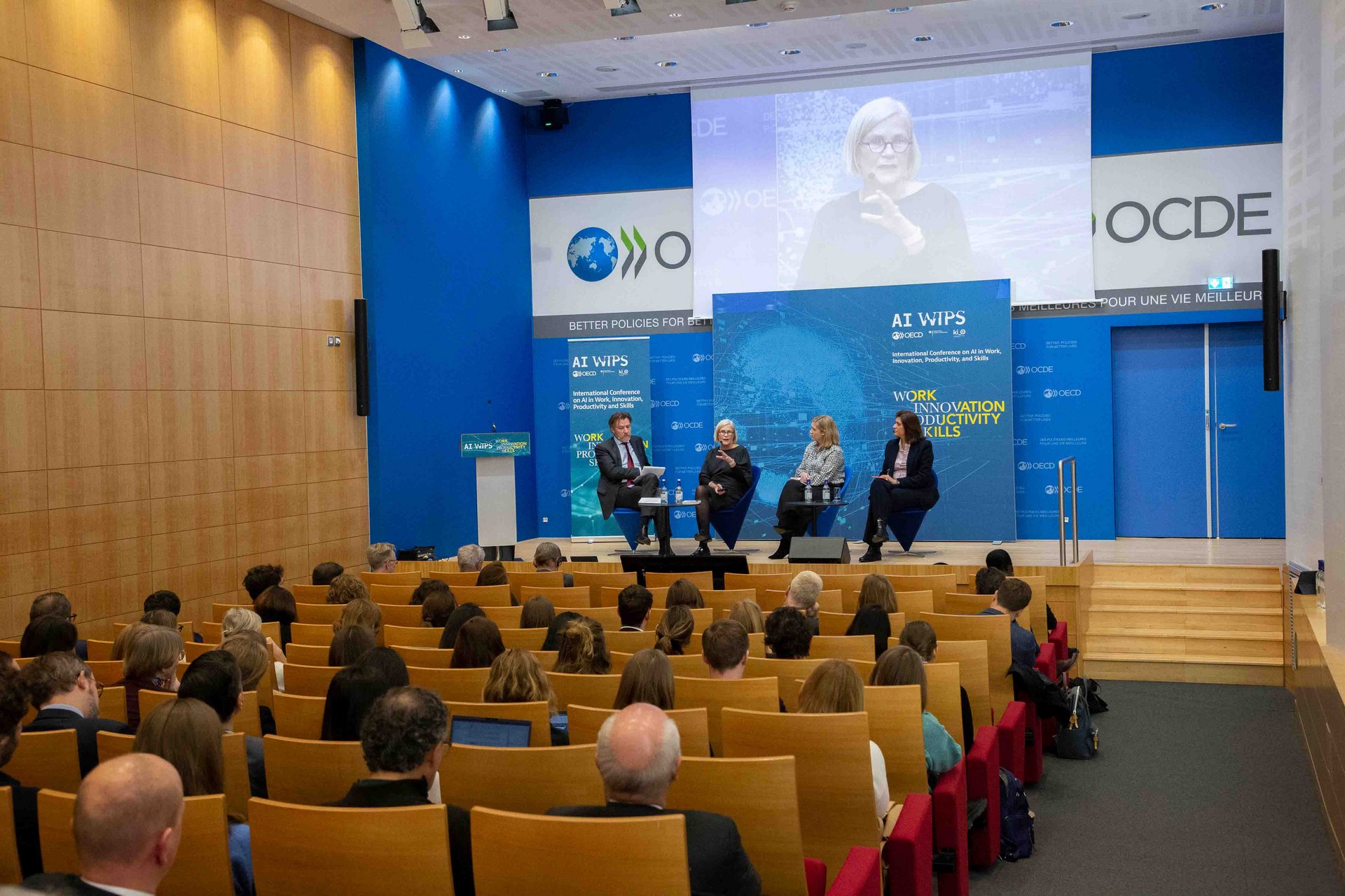 Das Eröffnungspanel der AI-WIPS-Konferenz mit Blick auf Publikum, Bühne und Teilnehmende des Eröffnungspanel der AI-WIPS-Konferenz.